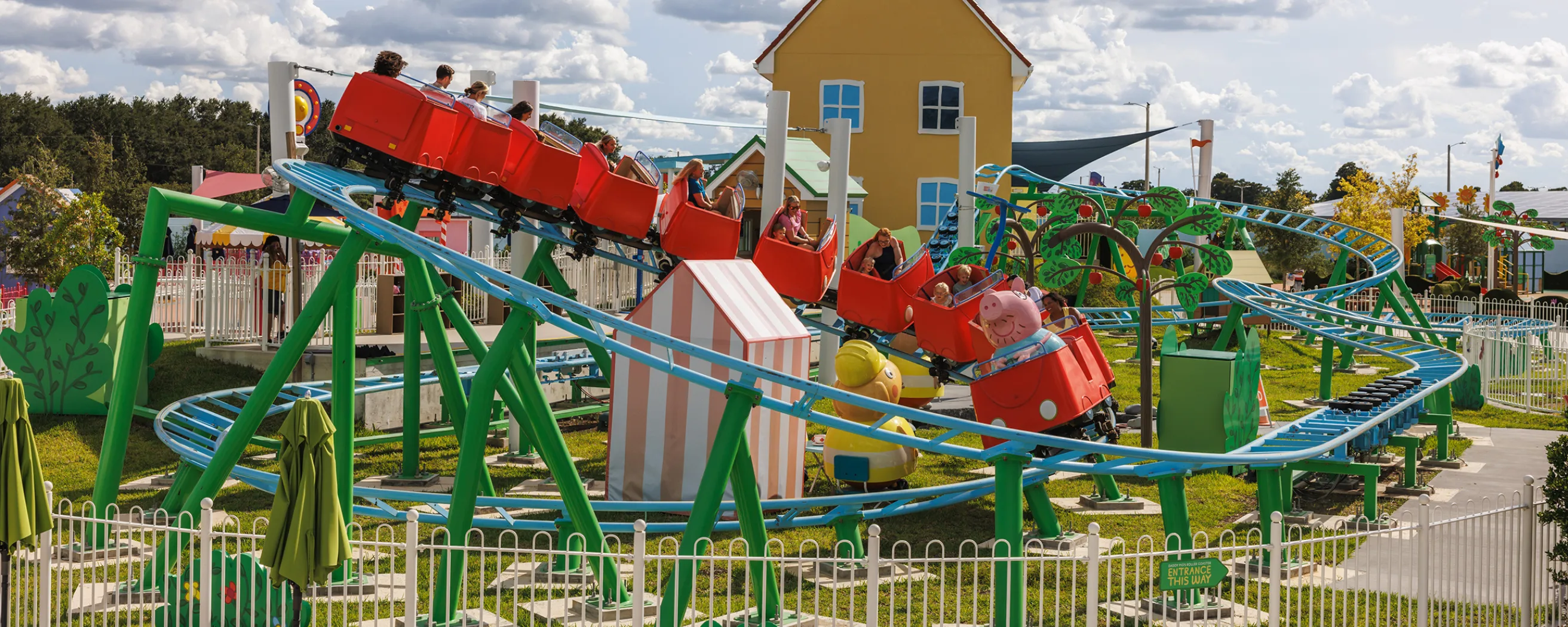 Guests enjoying a colorful roller coaster ride at Peppa Pig Theme Park in Florida